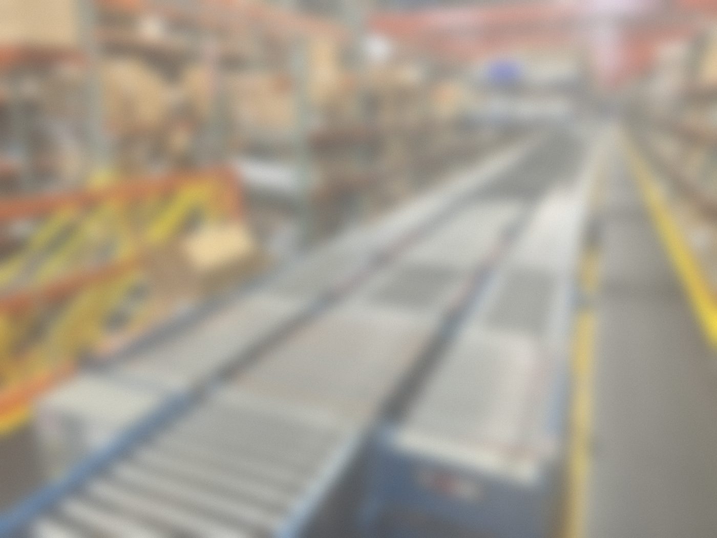 Zoned powered roller conveyor merge in a warehouse aisle